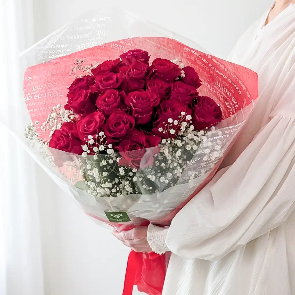プレミアムサイズの赤いバラとかすみ草の花束を人物が持つ